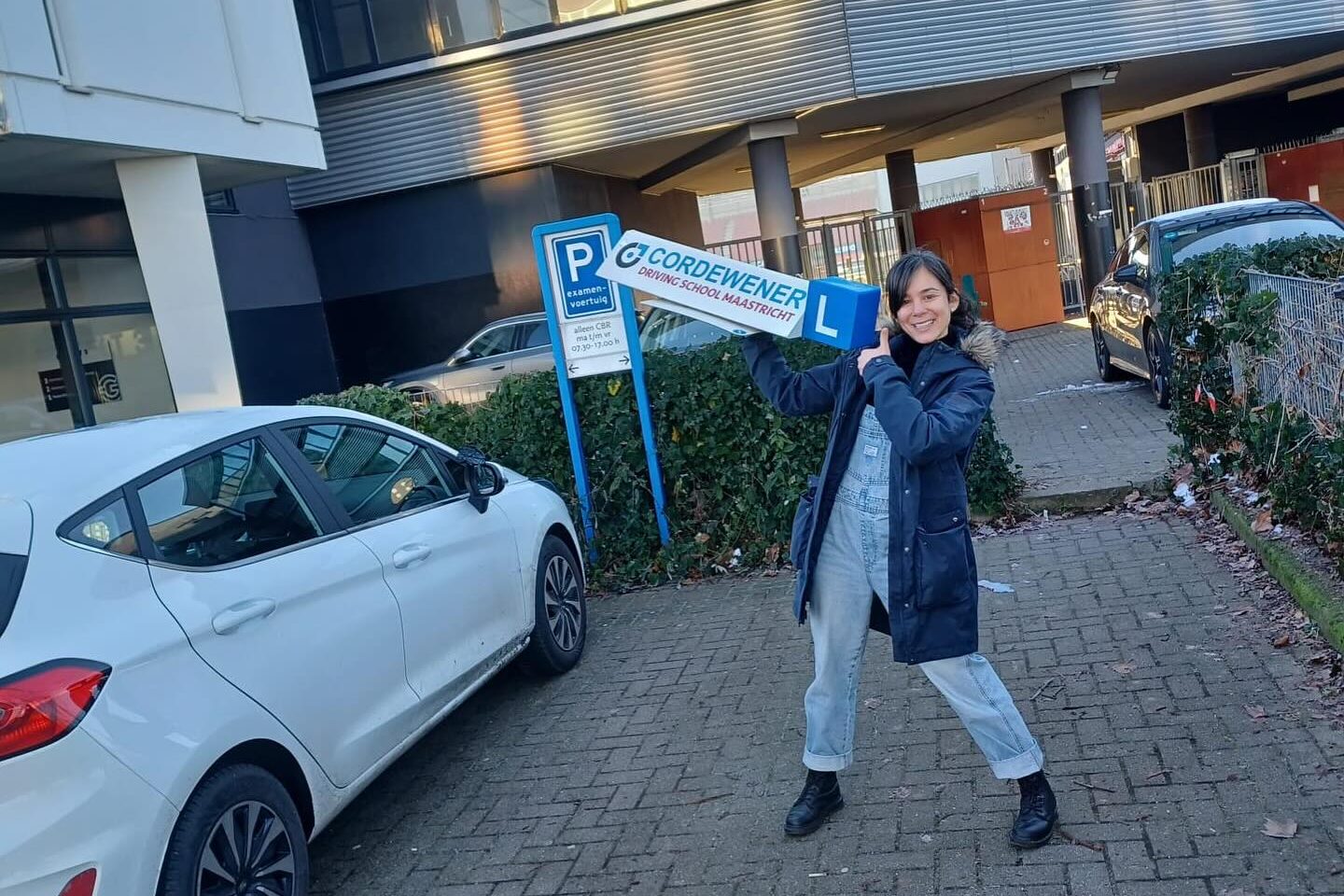 geslaagde leerling met bord van rijschool Cordewener