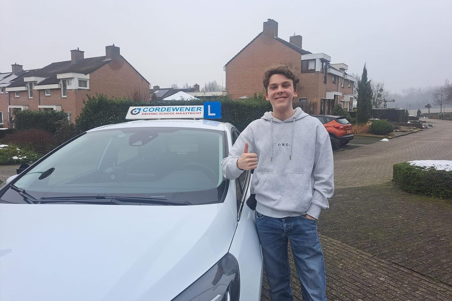 geslaagde leerling bij de auto van Cordewener met duim omhoog